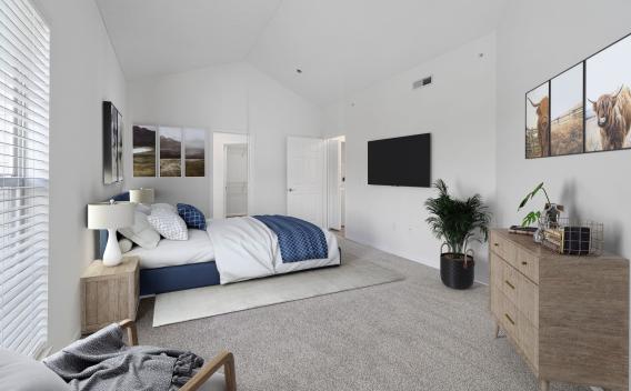 Bright bedroom with vaulted ceiling, bed with blue and white bedding, wall-mounted TV, wooden dresser, and highland cow art.