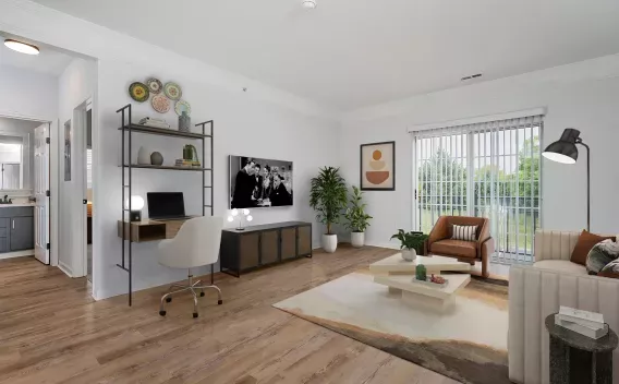 Modern living room with a desk, sofa, armchair, and TV. Hardwood floors and a large window shows green trees.