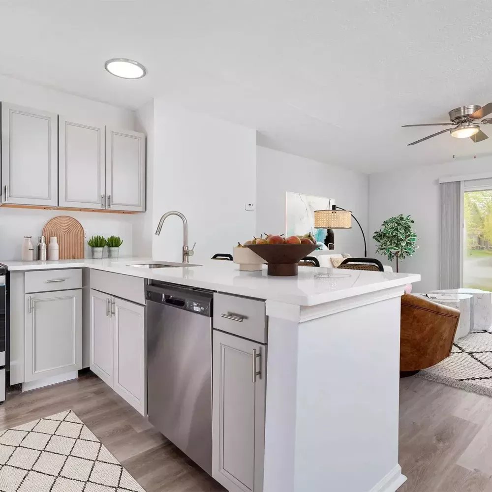 Modern kitchen with white cabinets, stainless steel appliances, island, and open view to a living room with a sliding door.