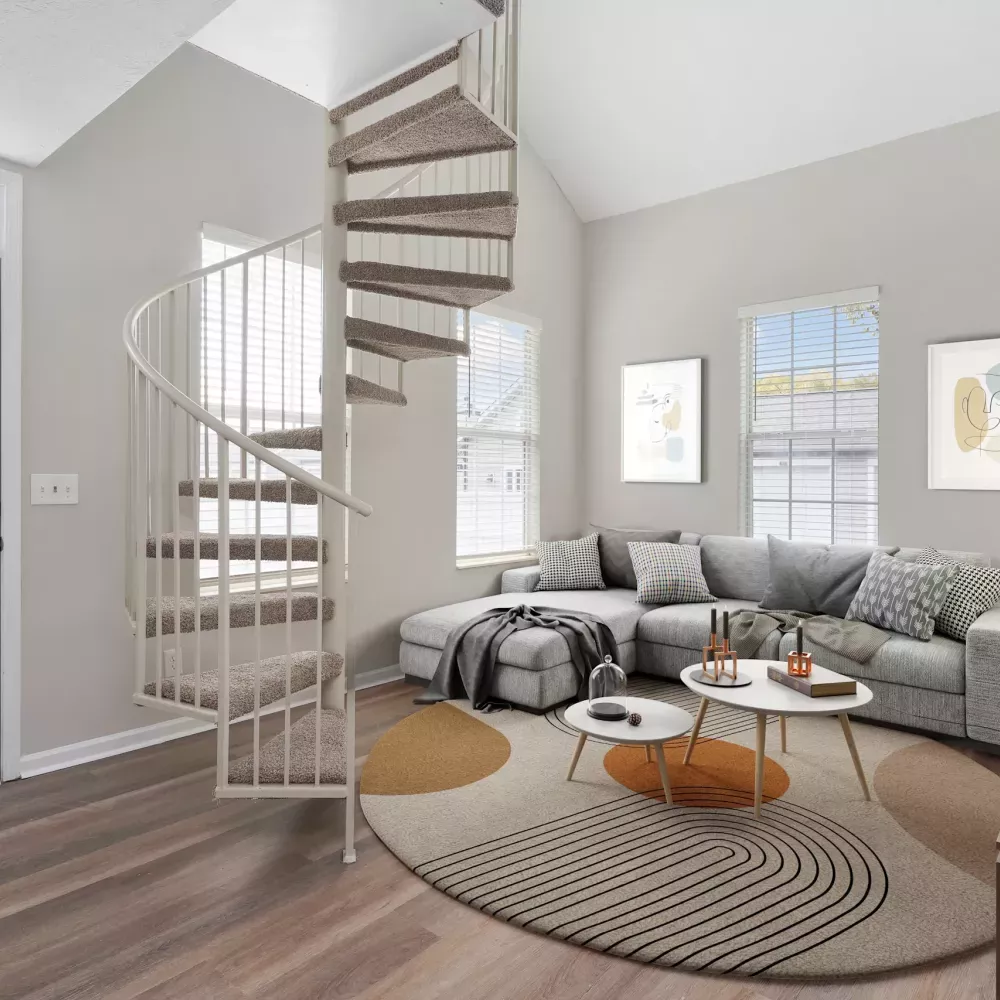 Modern living room with a white spiral staircase, gray sectional sofa, abstract art, and two round coffee tables.