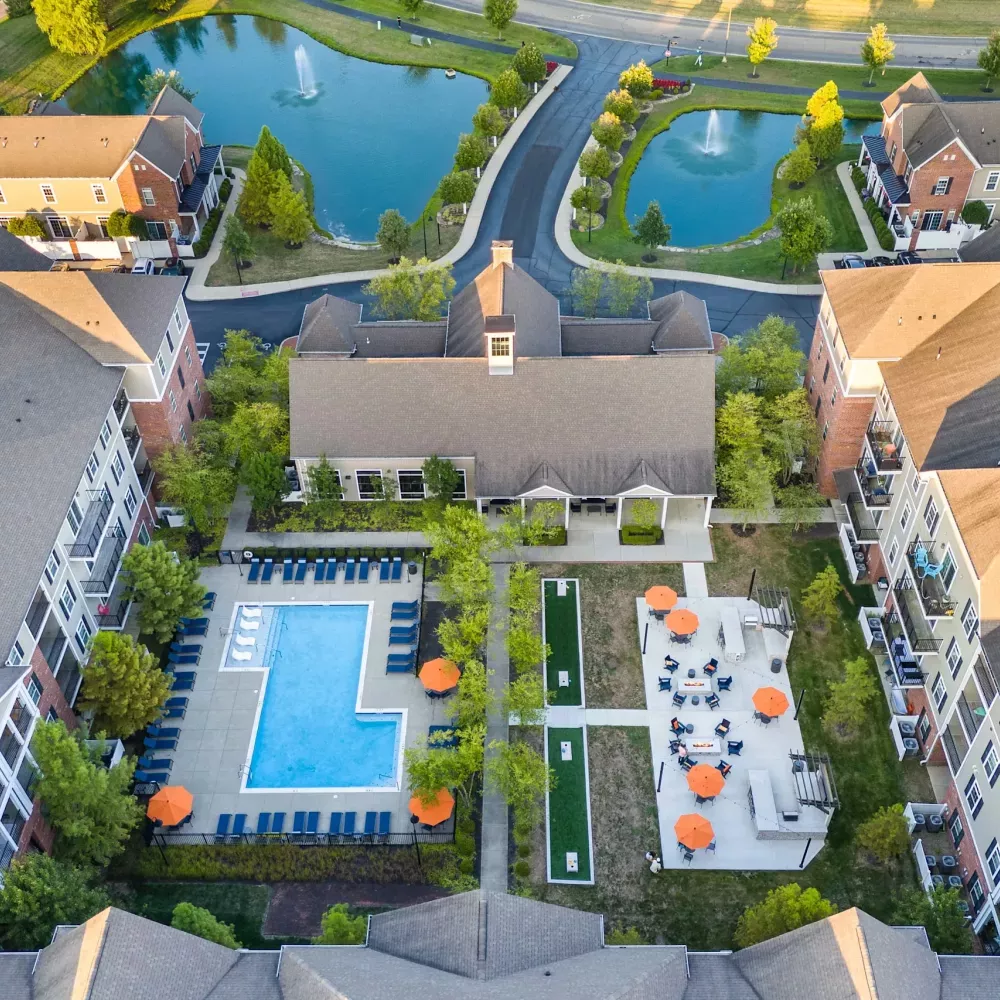 Aerial photograph of a residential complex with a large pool, mini-golf, outdoor seating, and two ponds with fountains.