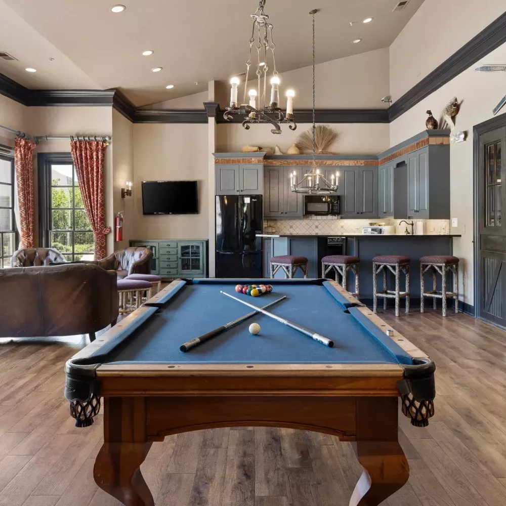 Rustic common room with a pool table, lounge seating, and a modern kitchen with dark cabinets and barn doors.