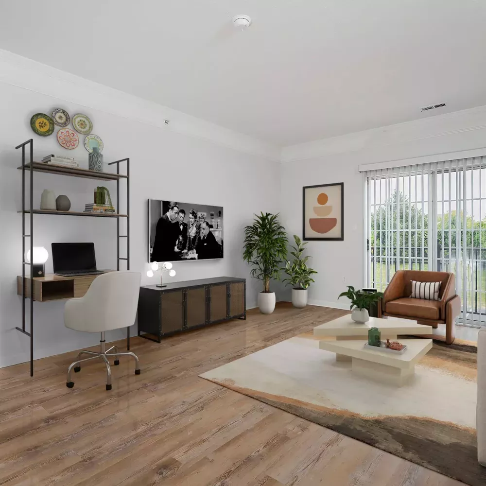 Modern living room with a desk, sofa, armchair, and TV. Hardwood floors and a large window shows green trees.